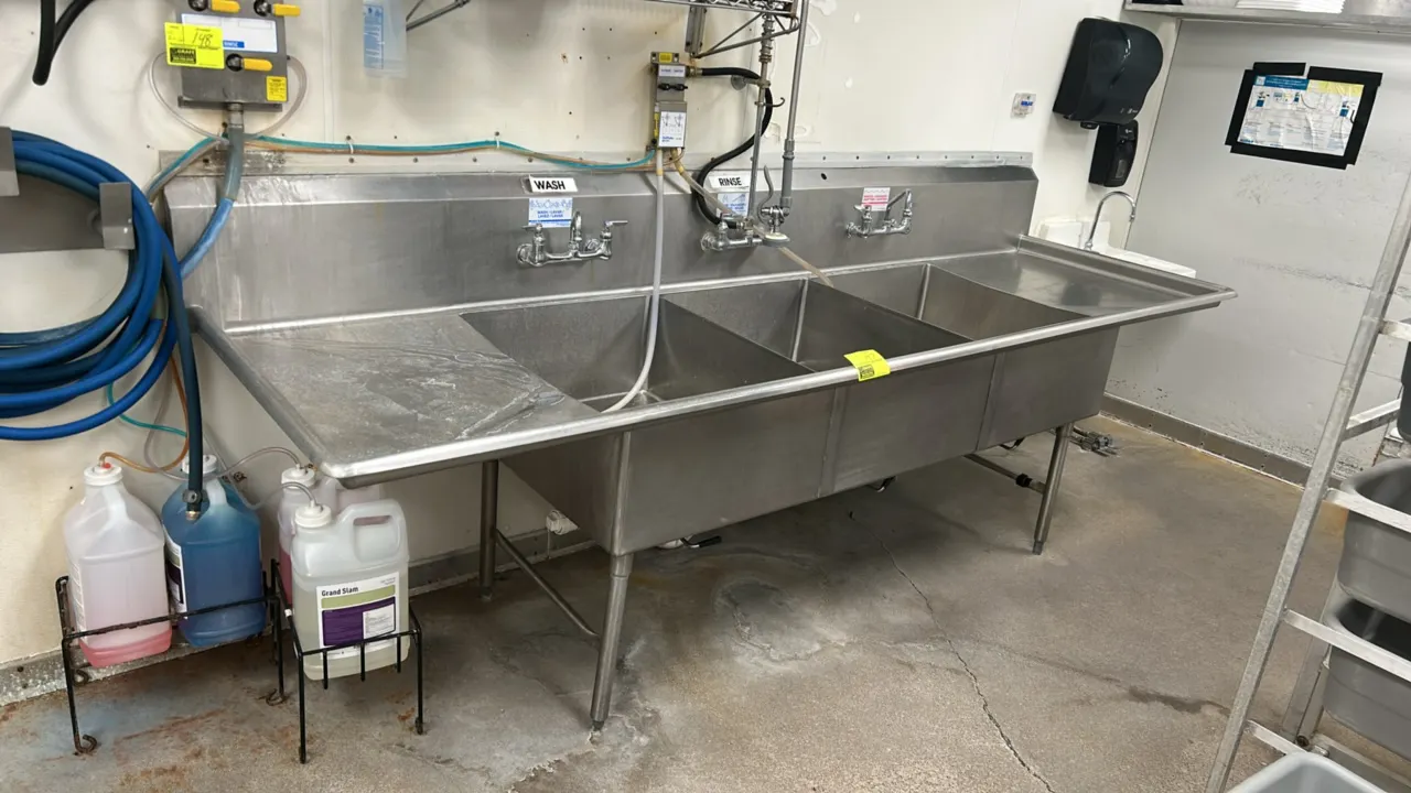 Stainless steel 3-compartment sink. Features left and right drainboards, integrated backsplash, (3) splash-mount faucets with center spring-style pre-