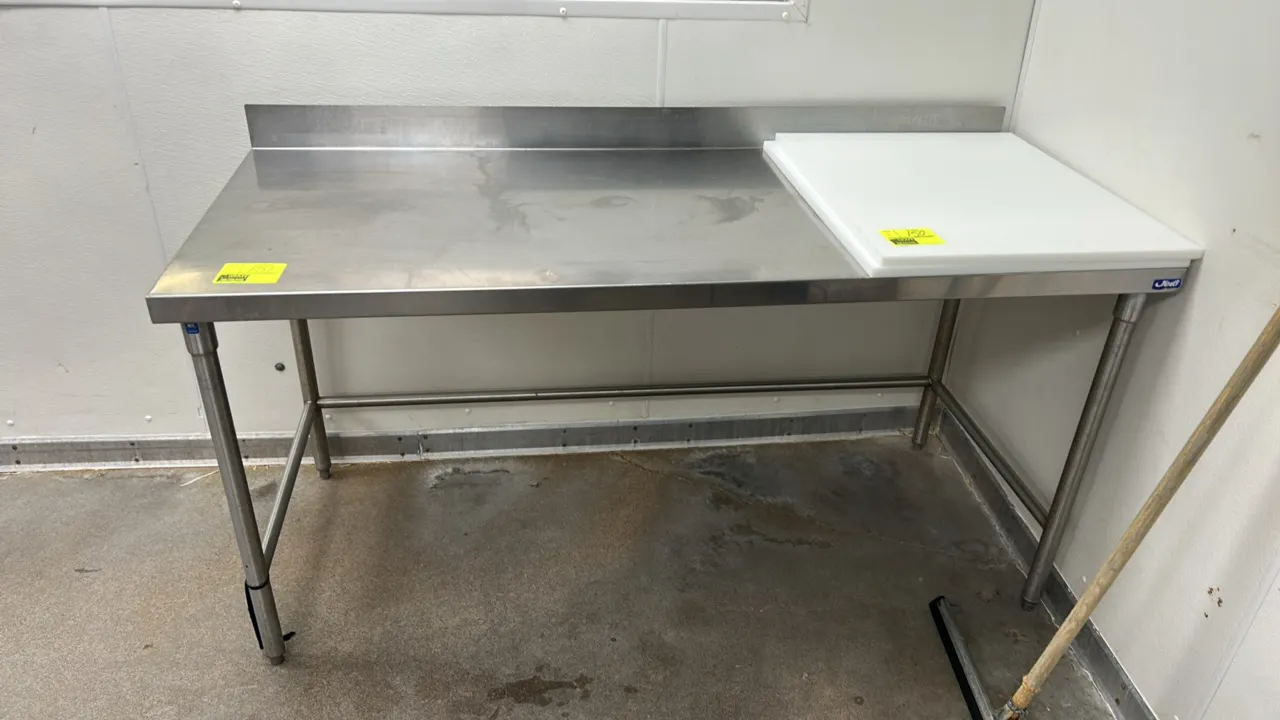 Stainless steel work table. Features a rear backsplash, removable poly cutting board, and 3-sided tubular cross-bracing. Dimensions: 72"L x 30"W. Moun