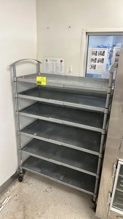 Metal 6-tier portable rack. Features solid metal shelves with lip edges and dual arched handles. 40" x 20". Mounted on swivel casters.