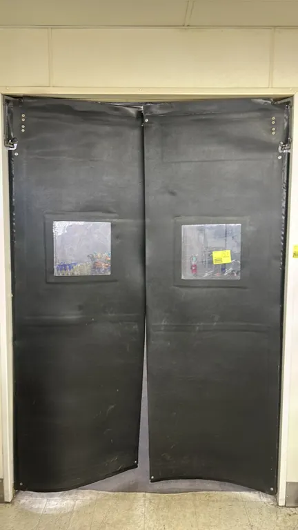 Poly impact swing doors. Features black textured flexible poly construction, clear center vision panels, and upper pivot hinge hardware. Dimensions: 3