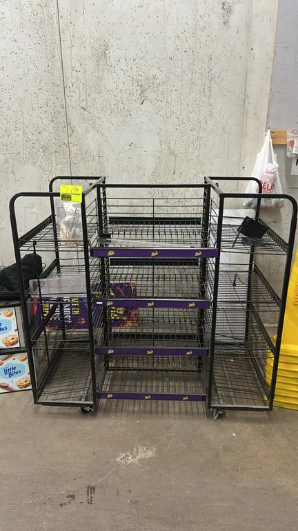 Metal wire 4-sided portable merchandiser rack. Features multi-tier wire shelving with shelf tag channels. Dimensions: 54" x 28". Mounted on casters. C