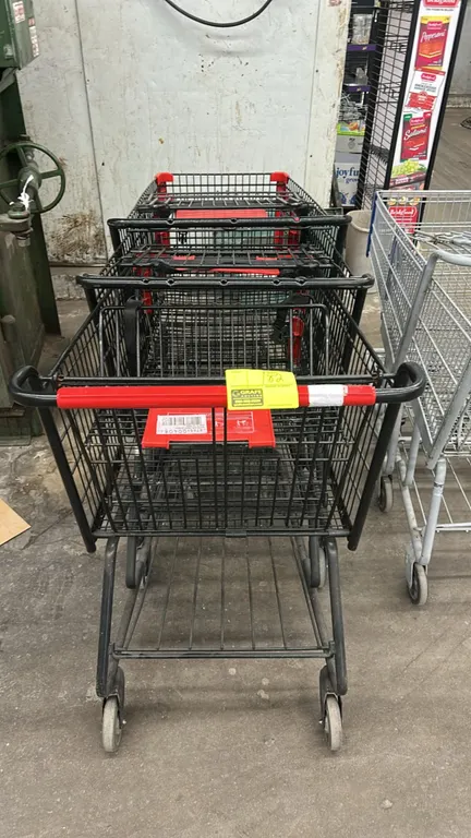 Metal wire shopping carts. Features black wire basket construction, folding child seat with red plastic seat and back, lower storage tray, red handle