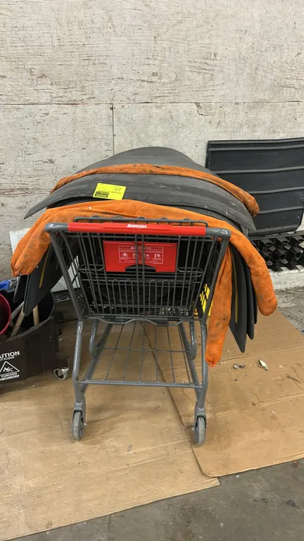 Package lot consisting of poly floor mats, absorbent socks, and a metal wire shopping cart. Shopping cart features a red plastic handle, folding child