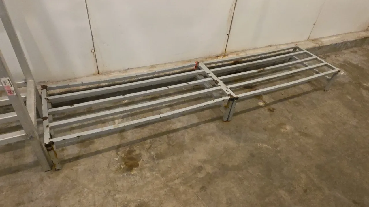 Metal dunnage racks. Features welded tubular slatted design. Dimensions: 4'L x 2'W each. Note: Shows rust, finish loss, and a bowed tube on one rack.