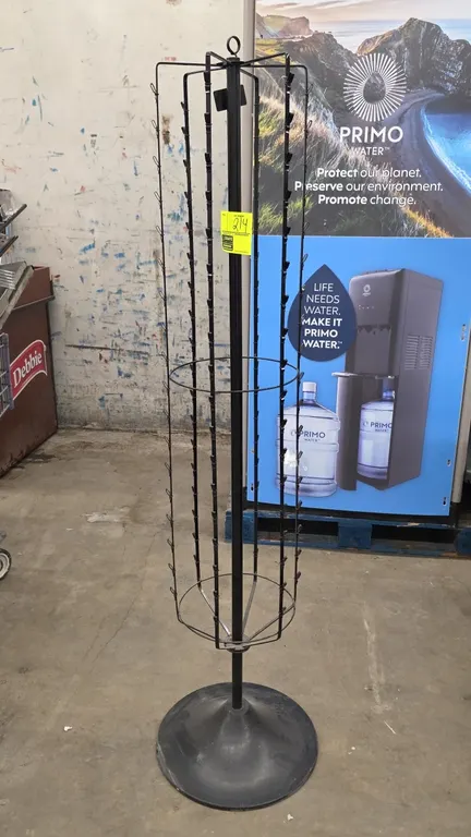 Metal rotating clip merchandiser. Features multi-strand wire hanging clips and top sign holder loop. 5'2"H. Mounted on a circular base.
