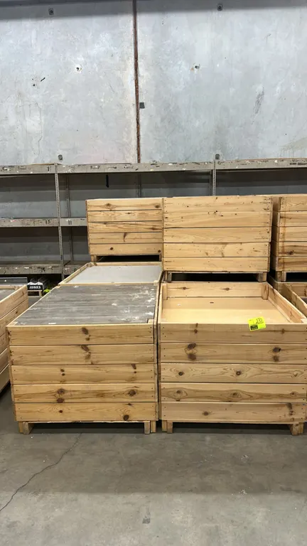 Wooden dump display tables. Features slatted wood construction, open display wells, and integrated fork runners for pallet jack or forklift transport.