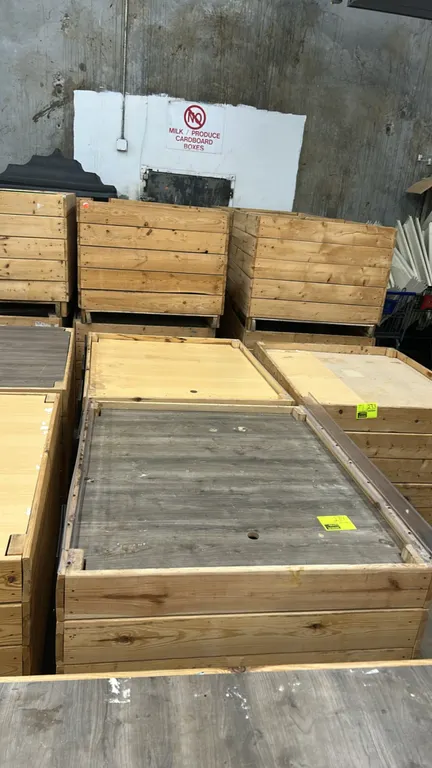 Wooden produce dump display tables. Features wood-slat side construction, faux wood grain deck surfaces, and pallet-style bases for pallet jack or for