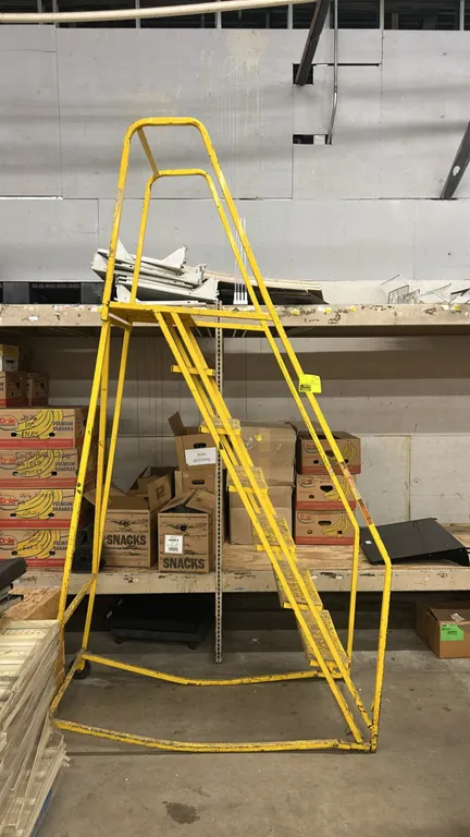 Metal rolling platform ladder. Features yellow painted steel construction, perforated grip steps, top platform, and safety handrails. 80"H. Note: Miss