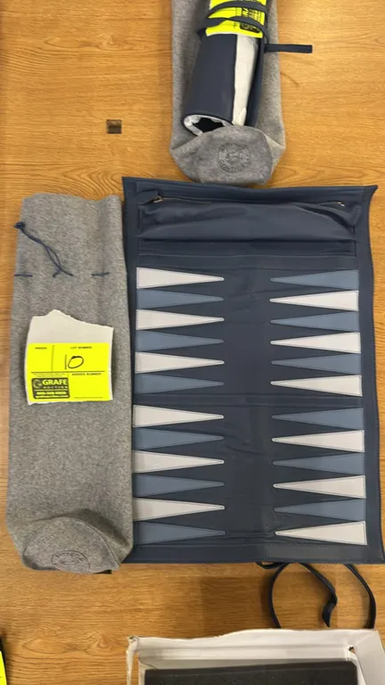Bottega Conticelli roll-up leather backgammon set. Features blue leather board with light blue and grey points, integrated zippered accessory compartm