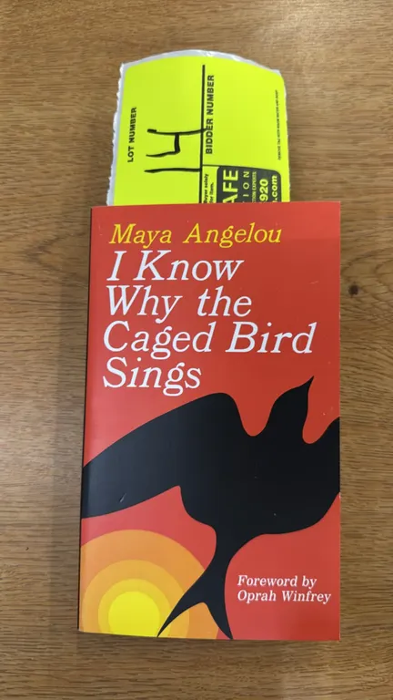 An "I Know Why the Caged Bird Sings" Paperback Book by Maya Angelou. (Ballantine Books) Softcover edition of the classic autobiography featuring a for
