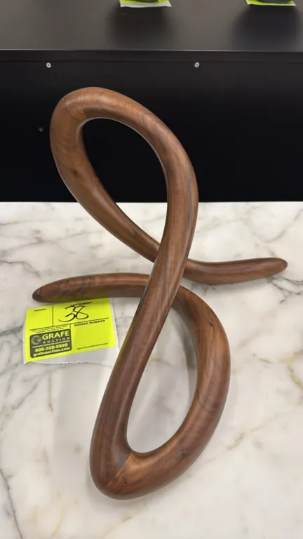 Custom carved wood wall sculpture. Features an abstract looping ribbon design with a smooth natural grain finish. Reverse is fitted with dual recessed