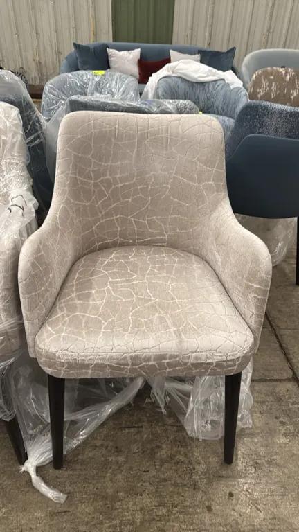 Adriana Hoyos Galapagos upholstered chairs. Features cream crackle-patterned fabric upholstery, contrasting cream back panel, integrated armrests, and
