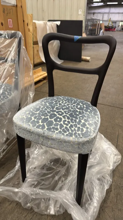 Porada Noemi dining side chairs. Features dark wood frames with open curved backrests, upholstered seats with blue patterned fabric, and tapered legs.