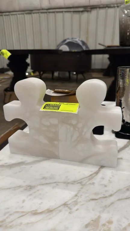 Genuine alabaster jigsaw bookends. Model: 3.31755. Features carved white alabaster construction in an interlocking puzzle piece design. Made in Italy.