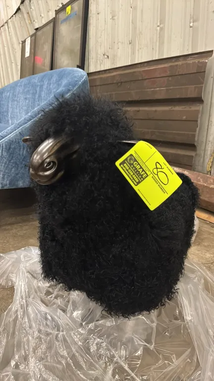 Interlude Home Leon sheep sculpture. Features black sheepskin upholstery with an antique bronze finish resin face and iron legs. Dimensions: 30" x 26"