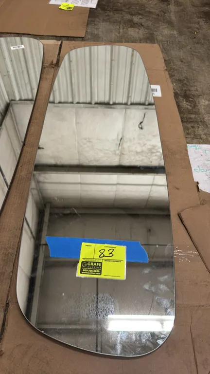 Custom-shaped wall mirror. Features an asymmetrical curved design, finished wood-grain back, and recessed metal mounting hardware. 48" x 15".