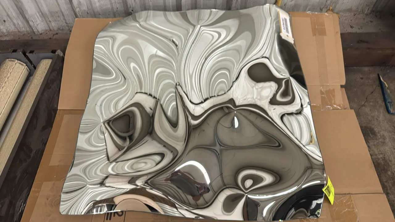 Dimensional mirror wall art. Features an undulating contoured design with a high-polish reflective mirrored finish. Dimensions: 42" x 40".