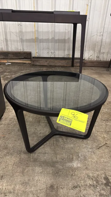 Wood side table with tinted glass top. Features a dark-finished wood frame with an inset circular tinted glass top and a three-leg joined base. Dimens
