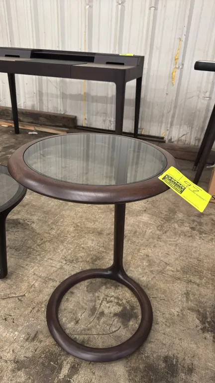 Ceccotti Collezioni Beside You side table. Features a dark wood frame with an inset round glass top, single curved upright support, and circular ring