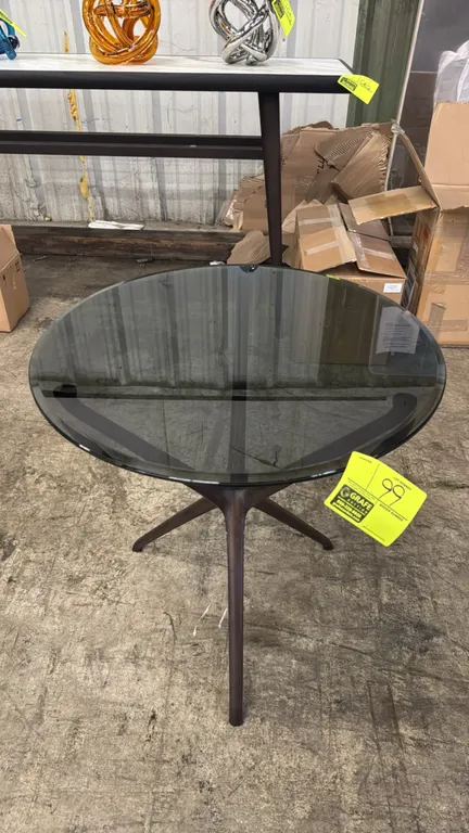 Ceccotti Collezioni Croix de Bois side table. Features a round tinted glass top supported by a sculpted dark wood tripod base. Dimensions: 24"x24".