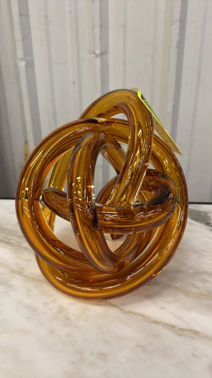 A SkLO Large Wrap Glass Sculpture. (SkLO) A continuous wound strand of hand-blown Czech glass forming an abstract knot, model FL120AMB in amber. Measu