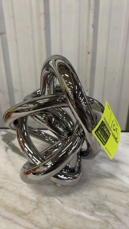 SkLO Wrap decorative object. Features a continuous looped knot design with a mirrored chrome finish. 11".