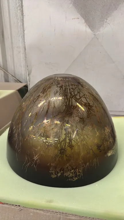 A Sabbia Gallery decorative etched glass bowl. Features an etched tree and branch landscape motif in amber and iridescent bronze tones. Measuring 16"