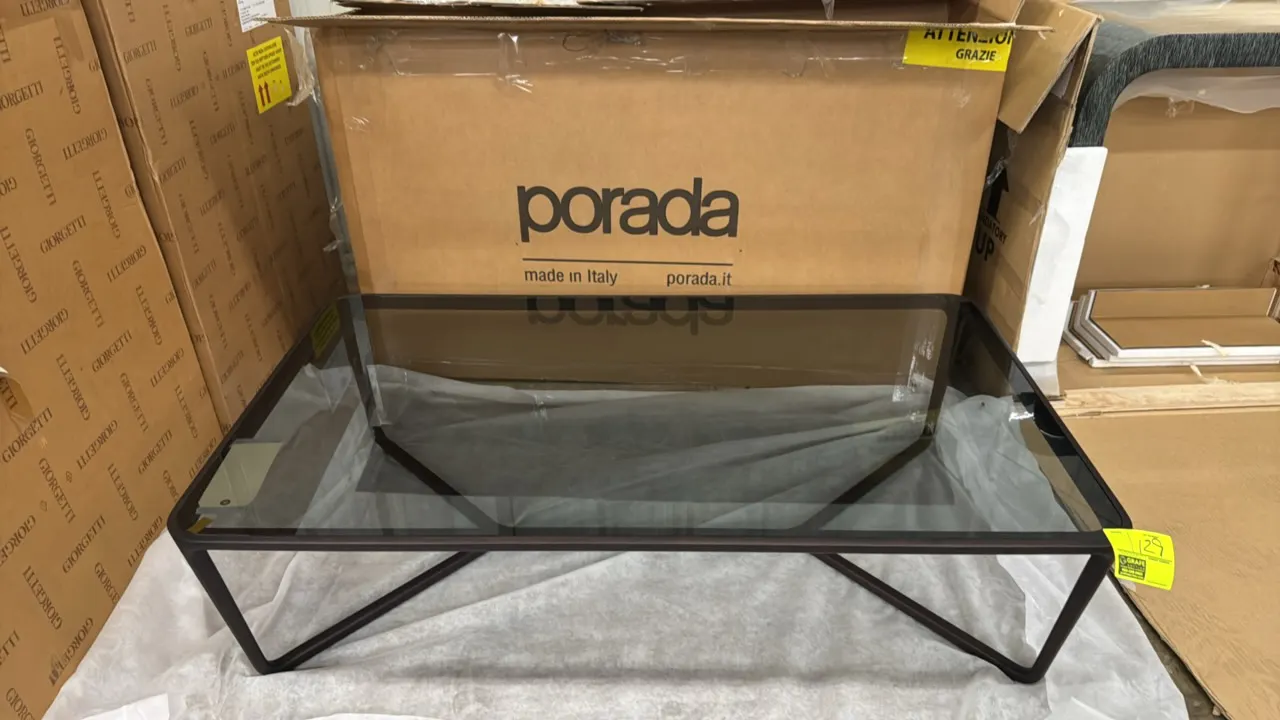 Porada wood coffee table. Features an inset tinted glass top and geometric dark wood base. Dimensions: 55"L x 32"W x 14"H.