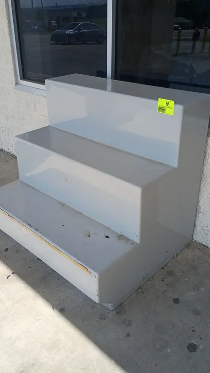 3-tier fiberglass merchandise display. Features a stepped multi-level riser design and molded fiberglass construction. Dimensions: 47" x 38" x 42".
