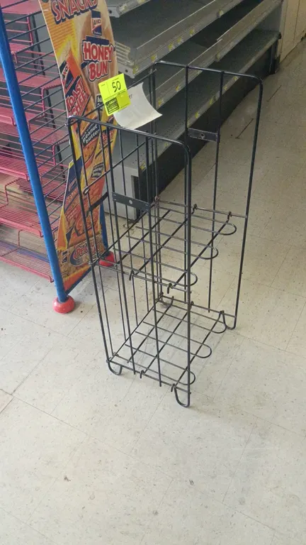 Wire newspaper merchandiser display rack. Features black wire construction with a 2-tier design. Freestanding base. Surrounding items not included.