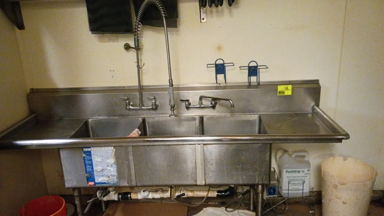 Stainless steel 3-bay wash sink. Features dual drainboards, integrated backsplash, overhead pre-rinse spray valve assembly, and swing spout faucet. Di