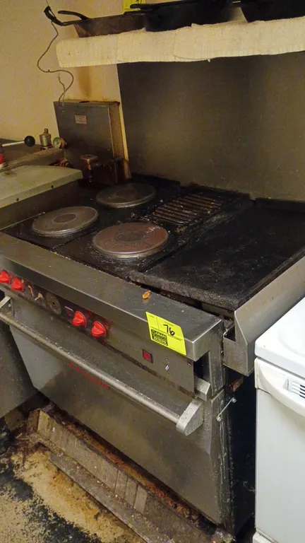 Vulcan commercial range with oven base. Features solid disk hot plates, top grate, flat top griddle, and lower standard oven. Stainless steel front an