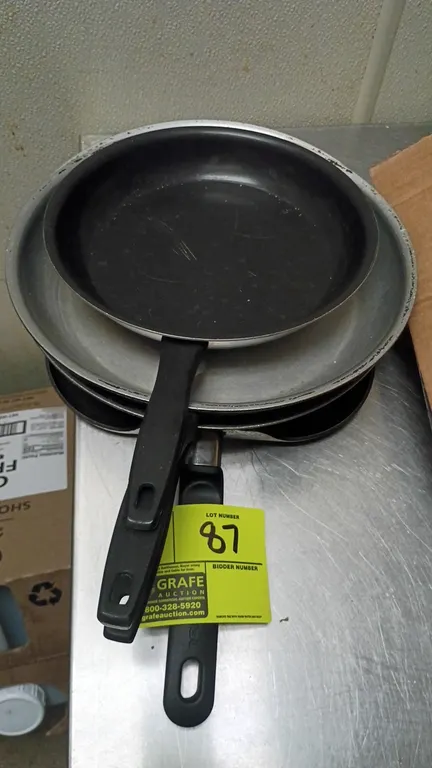 Assorted frying pans and griddle. Includes round aluminum fry pans, a round non-stick skillet, and a square non-stick griddle pan. Features composite