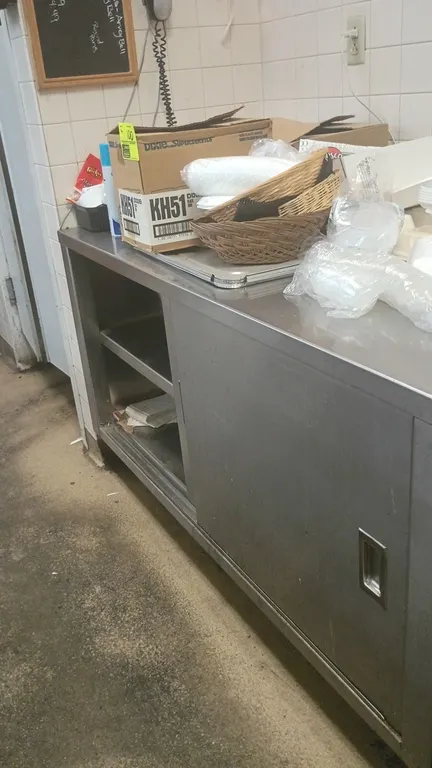 Stainless steel prep table. Features an enclosed base cabinet with sliding doors and interior mid-shelf. Dimensions: 60"L x 30"W x 38"H. Contents not