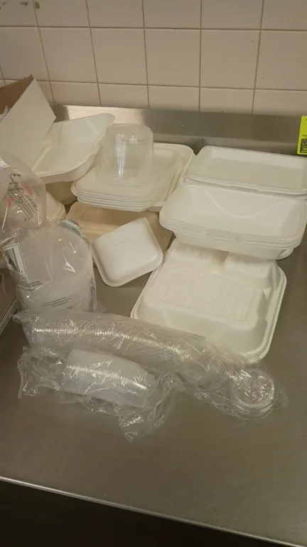 Assorted food service supplies. Includes plastic cutlery (forks and knives), hinged foam and plastic takeout containers, portion cups, lids, paper foo