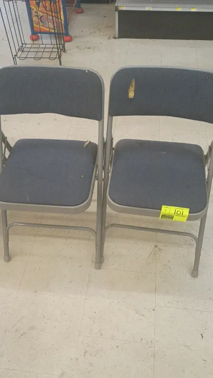 Padded folding chairs. Features blue fabric padded seats and backrests on gray metal folding frames. Note: Upholstery is torn on select chairs.