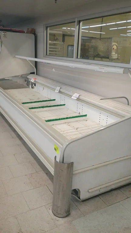 Kysor Warren M1A3-12U open-air display freezer. Features wire bottom rack shelving with dividers and canopy lighting. Dimensions: 12'L. S/N: 030864577