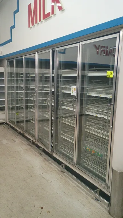 Tonka walk-in dairy cooler. Features 6 front reach-in glass display doors, solid walk-in door with diamond plate kick, multi-tier wire gravity racks,