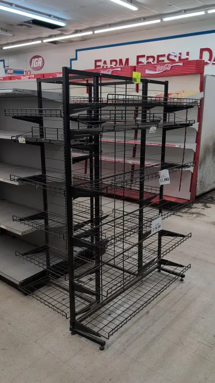 Metal merchandise display rack. Features double-sided black metal frame, adjustable wire display shelves with retaining lips, center wire divider grid