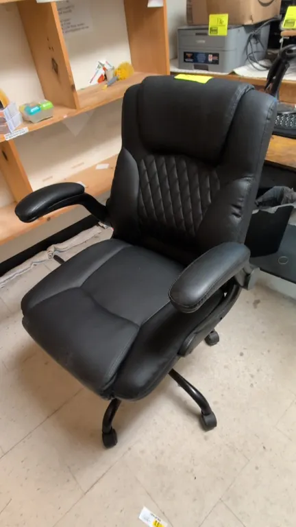 Faux leather cushioned office chair. Features black upholstery with diamond-quilted backrest accent, padded armrests, and pneumatic seat-height adjust