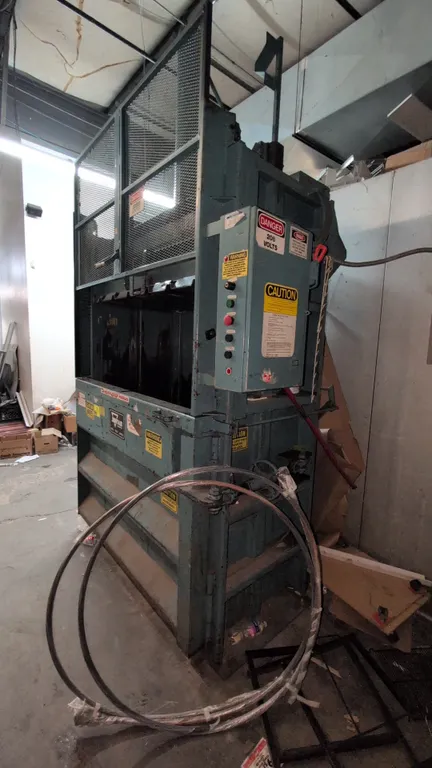 Marathon 6030 vertical baler. Features a left-hand swing door, wire mesh safety gate, push-button control panel, and hydraulic ram. Includes coils of