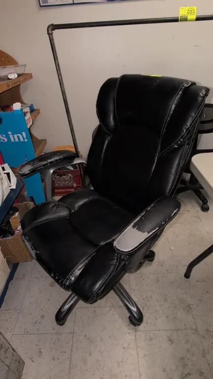 2016 cushioned executive office chair. Features black faux leather upholstery with contrast stitching, padded armrests, and pneumatic height adjustmen