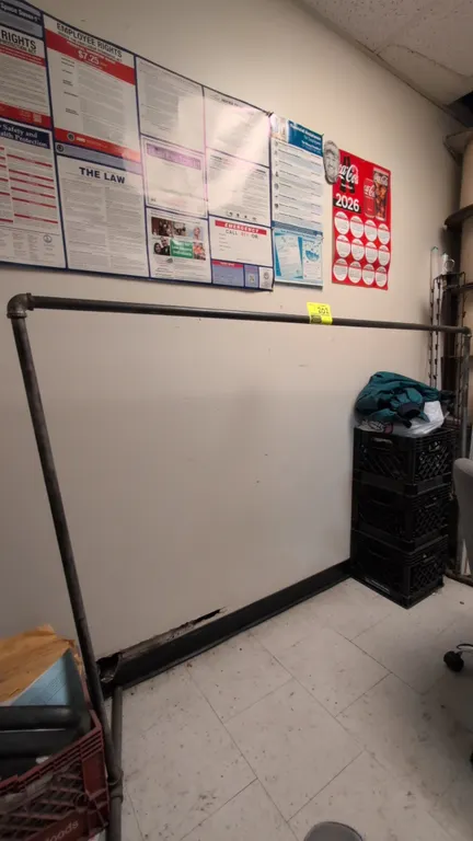 Industrial metal pipe garment rack. Features threaded pipe construction with elbow and tee fittings, single hanging rail, and dual stabilizer base fee