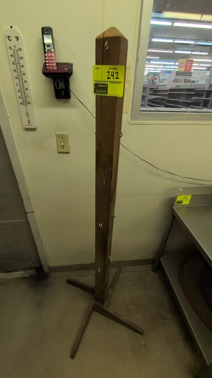 Wood coat rack. Features solid wood post construction with multiple metal hanging hooks. 67"H. Mounted on a 4-leg wooden cross base.