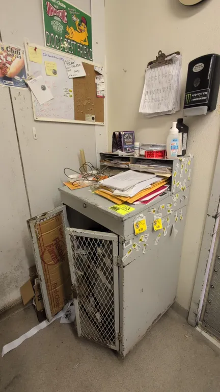 Metal shop desk with lower storage cabinet and combination whiteboard/corkboard. Desk measures 2' wide and features an upper organizer riser, center d