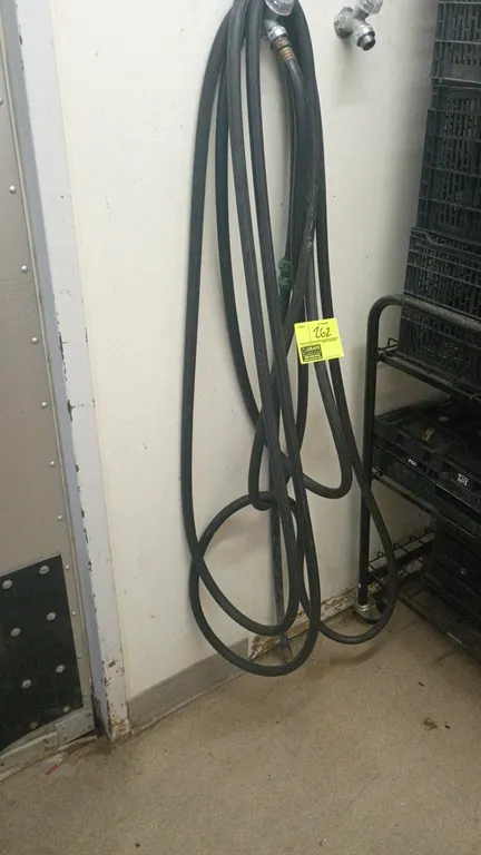 Black water hose. Features black rubber construction with threaded brass fitting. Wall spigot, cart, and background items not included.