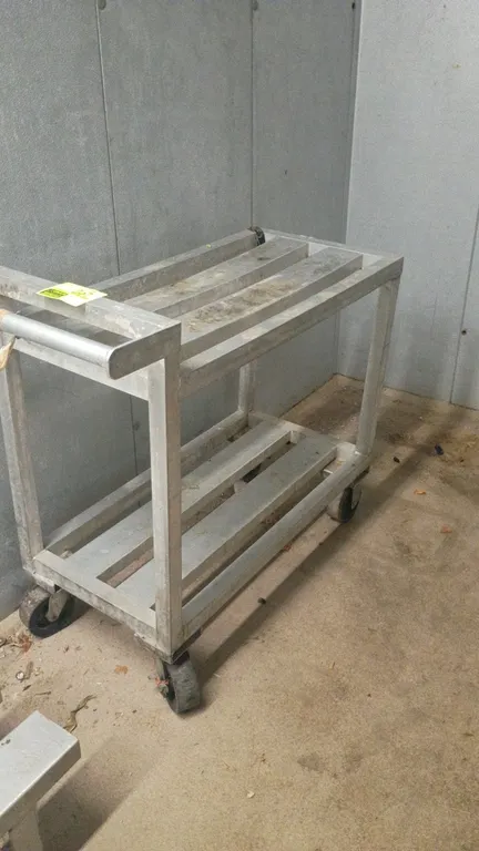 Aluminum portable cart. Features 2-tier slatted shelves and integrated tubular push handle. 41"L x 18"W x 36"H. Mounted on casters.