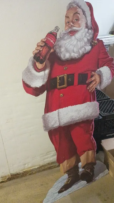 Christmas decor lot. Includes a Coca-Cola Santa Claus cardboard cutout standee and a box of assorted metallic gift bows in red, green, gold, and silve