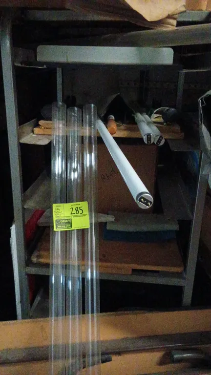 Assortment of fluorescent light bulbs and protective sleeves. Includes linear fluorescent tube lamps and clear plastic safety tube guards with assorte