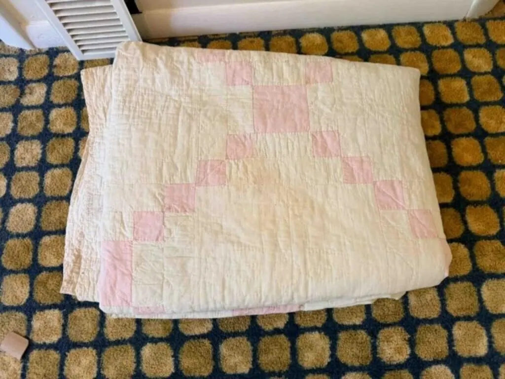 stack of older quilts, some have a lot of wear;